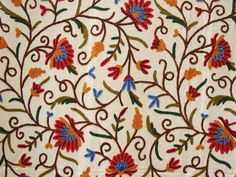 an embroidered fabric with colorful flowers and leaves on it's side, showing the intricate design