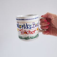 a person holding a coffee mug with the words world's best teacher on it