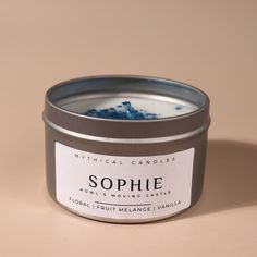 a candle that is sitting on a table in front of a brown background with the words sophie written across it