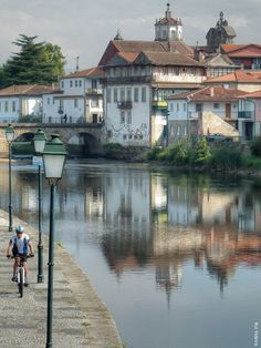 a man riding a bike down a street next to a river