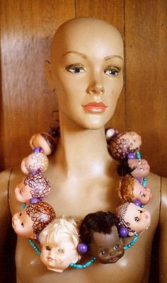 a mannequin wearing a necklace made out of dolls