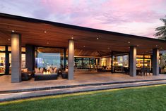 an outdoor living area with couches and tables under a covered patio at dusk or dawn