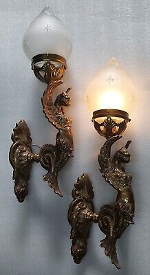 two antique brass sconces with glass shades on each side and an ornate design