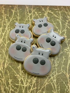 four decorated cookies in the shape of hippos on a green and gold background