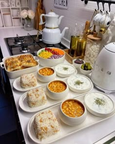 a kitchen counter topped with lots of bowls and plates filled with different types of food