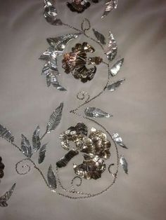 three pieces of silver metal on a white cloth with flowers and leaves in the center