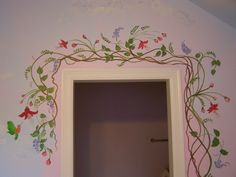 an open door with vines and flowers painted on the wall in a room that has pink walls