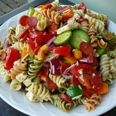 pasta salad with tomatoes, cucumbers, and other vegetables on a white plate