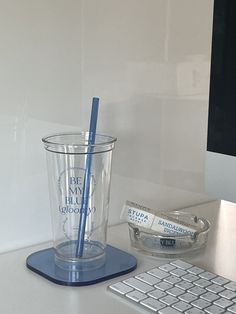 a cup with a straw in it sitting next to a keyboard and mouse on a desk