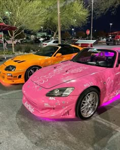 two pink cars parked next to each other in a parking lot