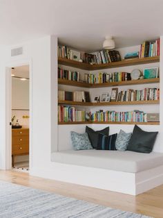 a living room filled with furniture and bookshelves next to a doorway that leads to a bedroom