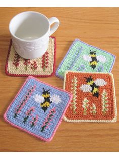 three crocheted coasters on a wooden table with a cup and saucer