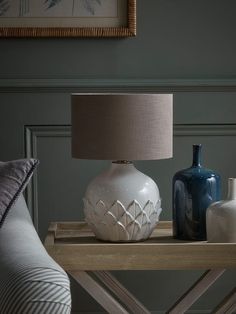 two vases sitting on a table next to a lamp