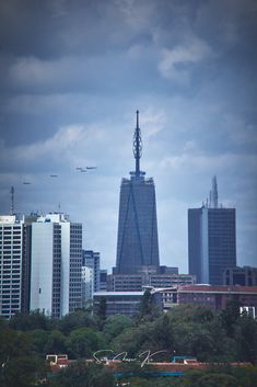 an airplane is flying in the sky over some tall buildings and trees with planes overhead