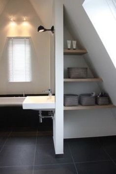 an attic bathroom with black tile flooring and white walls, along with open shelving