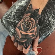 a black and white rose tattoo on the left hand