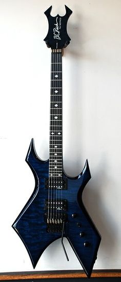 a blue electric guitar sitting on top of a wooden table next to a wall mounted clock