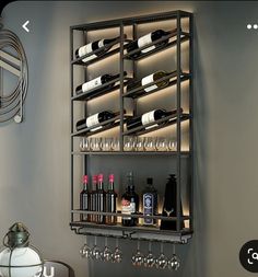 a wall mounted wine rack with many bottles and glasses on it next to a table