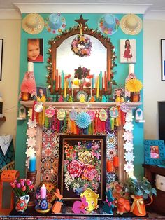 a colorful fireplace decorated with paper flowers, candles and other decorative items in front of a mirror