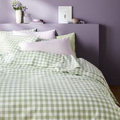 a green and white checkered comforter on a bed in a room with purple walls