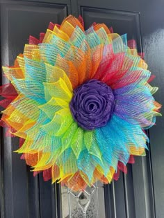 a multicolored wreath on the front door with a large flower in it's center