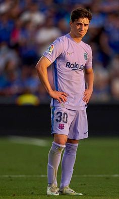 a soccer player is standing on the field with his hands on his hips and looking down