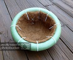 a cat bed with needles in it on a wooden decking area that has wood planks and boards