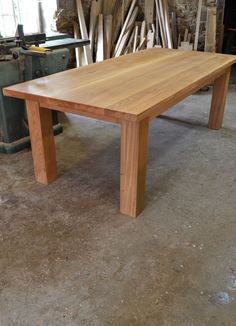 a wooden table sitting on top of a floor next to a pile of wood planks