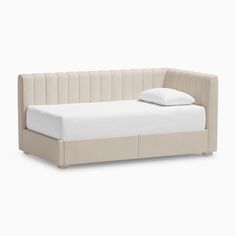 a bed with a white pillow on top of it and a light colored headboard