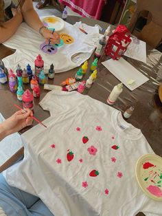 a woman sitting at a table with paint and crayons on it