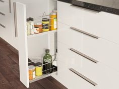 an open cabinet in a kitchen with spices and condiments on the bottom shelf