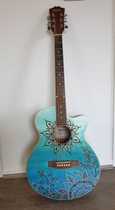 a blue guitar sitting on top of a hard wood floor next to a white wall