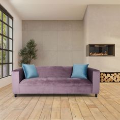 a purple couch sitting in front of a window next to a fire place on top of a hard wood floor