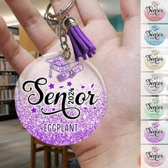 a hand holding a purple keychain with the words senior eggplant on it