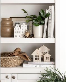 a white book shelf filled with books next to a potted plant and other items