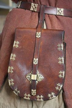 the back of a woman's brown leather purse with gold studded decorations on it