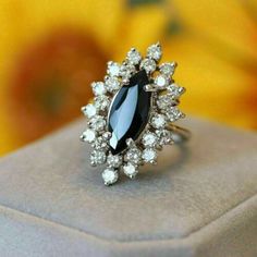 a black and white stone ring sitting on top of a box with flowers in the background