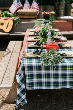 a long table is set up with place settings for an outdoor party or picnic event