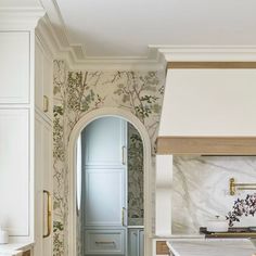 a kitchen with white cabinets and marble counter tops, along with an arched doorway leading to another room