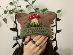 a woman covering her face with a knitted hat