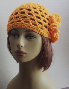 a mannequin head wearing a yellow crochet hat with flowers on it