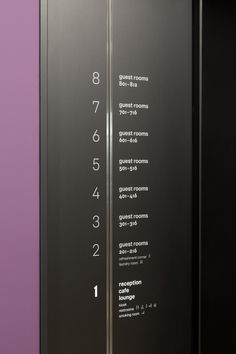 an elevator with numbers and times on the glass wall in front of purple walls,