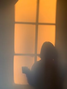 the shadow of a person sitting in front of a window with a remote control on their lap