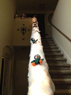 there are stuffed penguins on top of the white fluffy pole next to the stair case