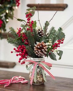 a mason jar filled with holly, pine cones and candy canes sitting on a table