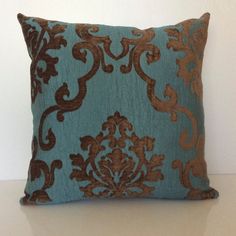 a blue and brown pillow sitting on top of a white table next to a wall