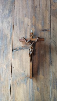 a wooden crucifix with a statue of jesus on it's side