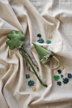 two green hats are laying on a white cloth with shamrocks and beads around them