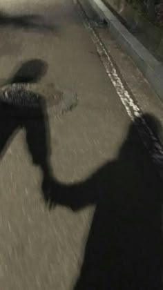 the shadow of a person holding an umbrella over their head while walking down a street