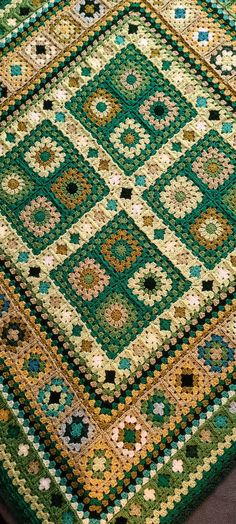 a green, yellow and brown rug with squares on the top is laying on a wooden floor